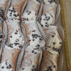 A tray of CO-080 Ricotta cannoli with chocolate chips, filled with creamy ricotta and topped with mini chocolate chips, neatly arranged in paper wrappers.