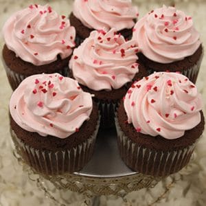 Six VC-039 Display Valentine chocolate cupcakes with white chocolate mousse filling are arranged on a silver stand against a light, textured background.