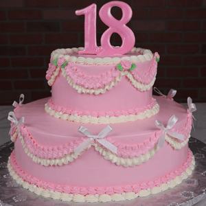 The TC-000M is a two-tiered pink and white birthday cake featuring ruffles, bows, small roses, and topped with a large pink number 18.