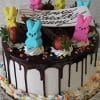 The EA-014 is a chocolate-dripped birthday cake topped with marshmallow bunny Peeps, chocolate pieces, strawberries, a white “Happy Birthday” plaque, rainbow star sprinkles, and whipped cream around the base.