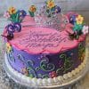 The SC-028 Princess Crown is a round purple and pink birthday cake, decorated with fondant flowers, butterflies, swirls, and a silver tiara. “Happy Birthday Maya” is written in cursive on top. The cake sits on a silver tray.