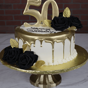 The Golden 50th cake features white icing with a gold drip, a large gold 50 topper, black fondant roses, gold leaves, and "Happy Birthday" on top, presented on a gold stand against a brick wall background.