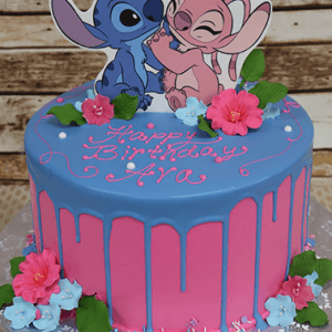 The CB-010G is a pink and blue birthday cake with blue icing drips, decorated with pink and blue flowers, green leaves, cartoon cutouts of Stitch and Angel on top, and "Happy Birthday Ava" written in pink icing.