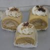 Three AP-045C Pumpkin Roulade cakes with cream filling, each topped with whipped cream and chopped nuts, are displayed on a silver surface.