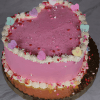 The VC-013D is a heart-shaped pink cake with white frosting along the edges, topped with heart-shaped candies and red, pink, and white sprinkles on a gold cake board.