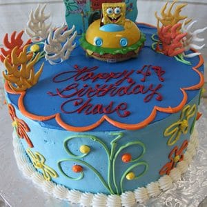 SC-038 Sponge Bob: Round blue birthday cake with sea plants, colorful icing, and a SpongeBob SquarePants figurine in a car topper. Finished with “Happy 4th Birthday Chase” in red script.