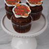 Three CC-098a March Madness Chocolate Cupcakes with white filling and “March Madness 2025” toppers are displayed on a white cake stand against a marble background.