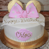 The CB-001G cake is white with a gold ribbon base, topped with gold mouse ears and a pink polka-dot bow. "Happy Birthday" is written on the cake, along with a plaque featuring "Chloe" in gold.