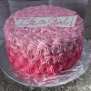 The BD-062 Pink rosette is a round cake with pink buttercream rosettes and an "It's a Girl!" sign on top, presented on a silver cake board.