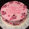 The CB-025C is a round pink birthday cake with pink and white polka dots, cupcake decorations, and "Happy 6th Birthday Krishna" in pink icing, presented on a silver-patterned board.
