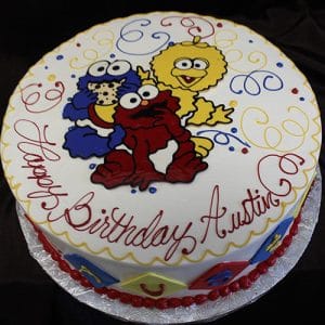 CB-003A: Round birthday cake featuring Cookie Monster, Elmo, and Big Bird from Sesame Street with colorful swirls and "Happy Birthday Austin" in red icing.