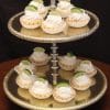 A two-tiered silver stand displays Keylime Tarts topped with whipped cream and lime slices. The dark background highlights the vibrant desserts.