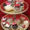 The VC-018 Valentine Pastries set features assorted mini cakes and pastries with heart decorations and "Love" lettering, displayed on a two-tier dessert stand against a red background with white dots.