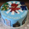 CB-009F is a round blue birthday cake featuring PJ Masks characters on top, cityscape silhouettes around the sides, and "Happy Birthday Xaydin" written in white on the surface.