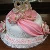 The BD-055B Pink Swag is a round white birthday cake with pink draped fondant, gold-edged pink flowers, a gold "90" topper, and "Happy Birthday Irene" written on the base.