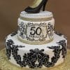 TC-089: A two-tier white cake with black ornate designs, gold accents, a gold and black high-heeled shoe topper, and “50 Fabulous” on the upper tier.