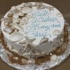 BR-048: Round cake adorned with edible seashells and starfish, "Best Wishes Amy and Chris" in blue icing, edged with brown sugar sand and presented on a silver foil board.