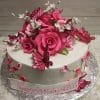 The BD-060G "Shades of Pink Roses/Butterflies" cake features white frosting, pink and red fondant roses, white flowers, pink butterflies, green vines with pink flowers on the sides, and a "Happy Birthday Jill" plaque in pink script.