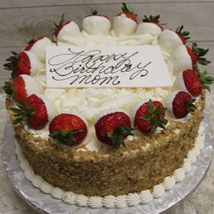 A round BD-008C Carrot cake with white frosting, crushed nuts on the sides, and strawberries dipped in white chocolate. A white card on top says “Happy Birthday mom” in elegant script.