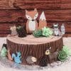 The BB-048 cake is designed like a tree stump with chocolate frosting, green succulent decorations, and edible woodland animal toppers—fox, raccoon, owl, squirrel, hedgehog, and deer—set against a wooden background.